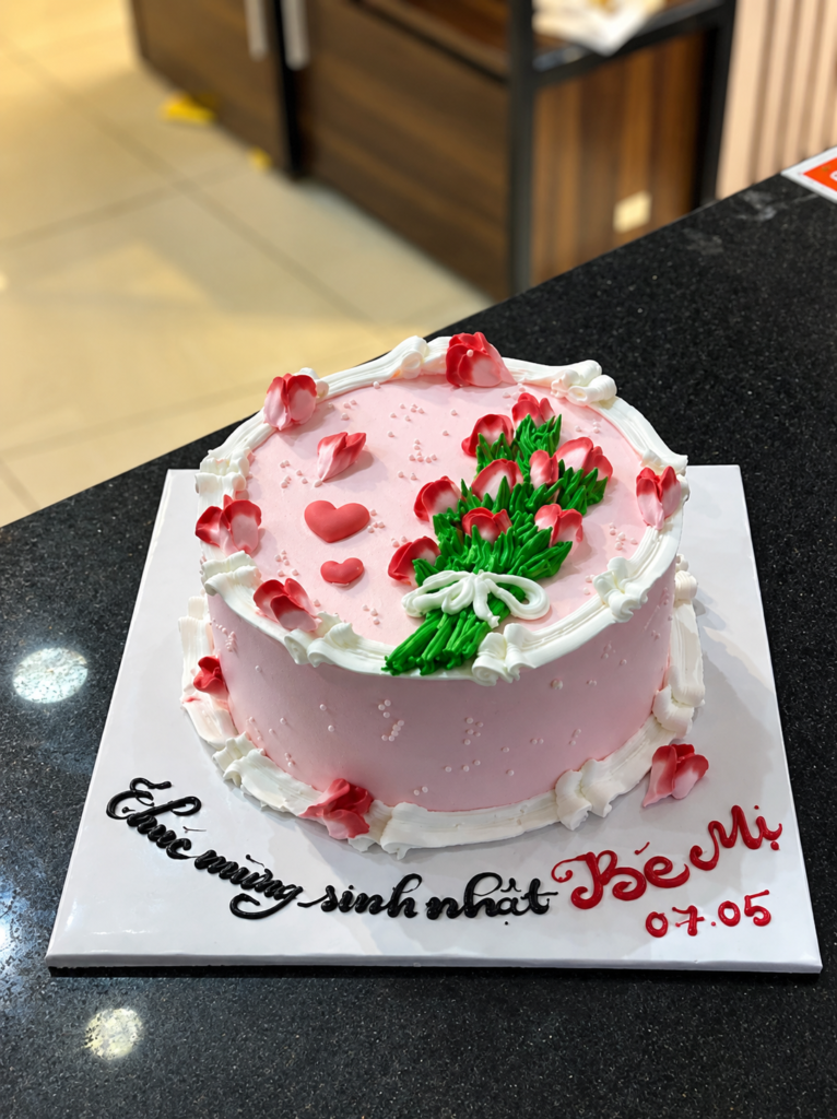 Bánh kem tone hồng trang trí bó hoa đỏ.